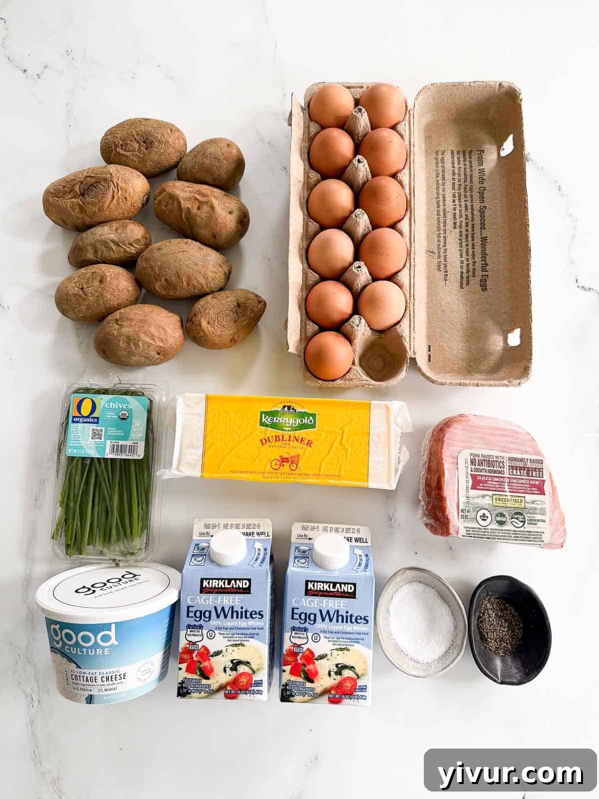Collection of fresh ingredients for ham and cheese egg casserole, including potatoes, ham, eggs, and cheese