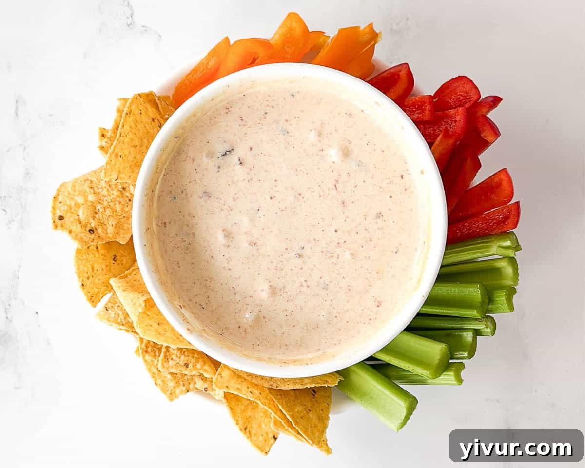 Protein-Boosted Cottage Cheese Queso 7 Step 4: High Protein Queso Dip served warm in a white bowl, ready to be enjoyed with a side of colorful tortilla chips.