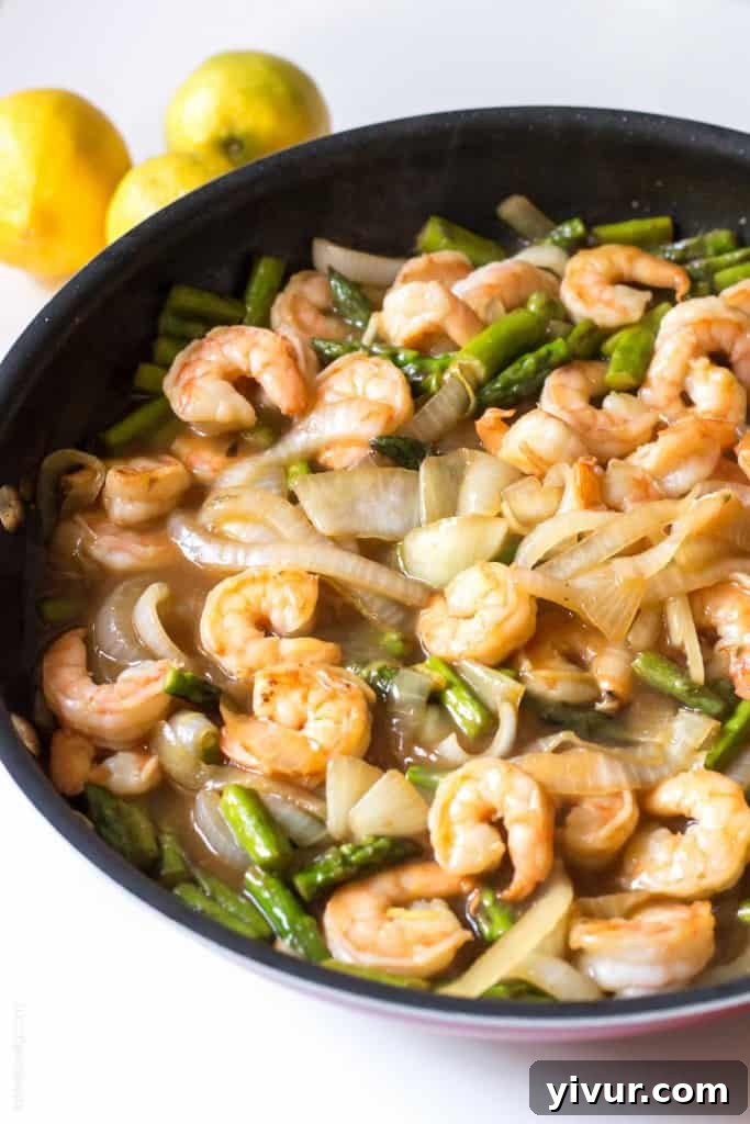 Close-up of lemon shrimp and asparagus stir fry being cooked in a large pan