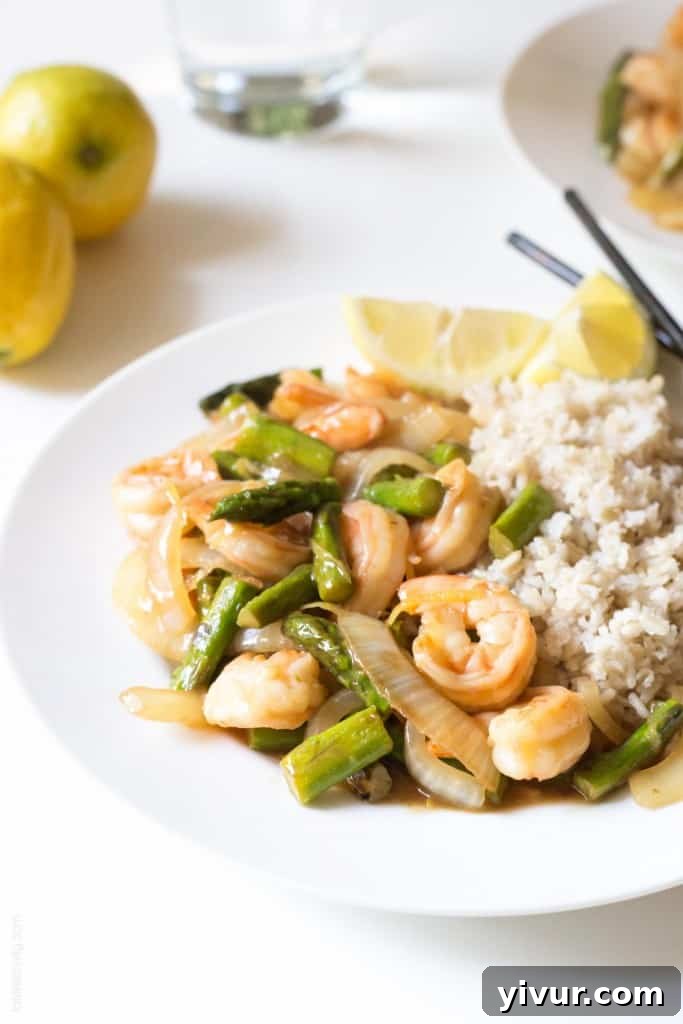 A serving of Lemon Shrimp & Asparagus Stir Fry with rice, presented beautifully