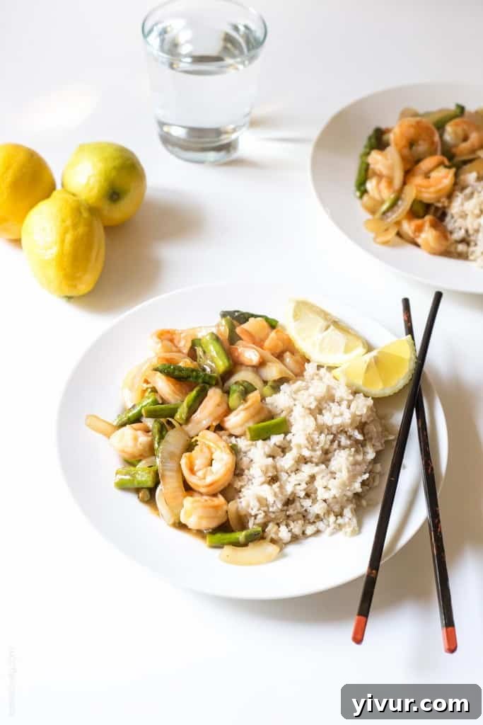 Lemon Shrimp & Asparagus Stir Fry plated on a white dish, garnished with lemon zest
