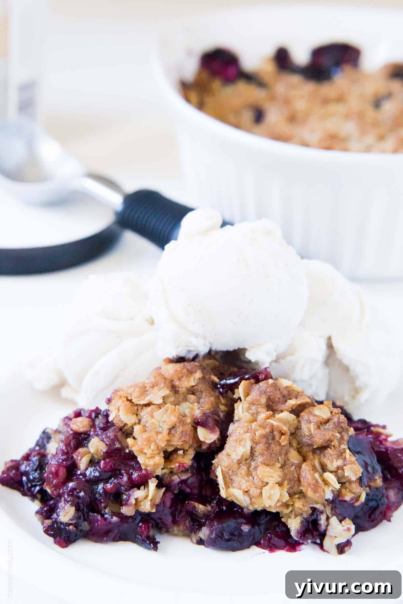 Quick Triple Berry Crumble from Frozen 2 A vibrant berry crumble recipe topped with a scoop of vanilla ice cream, showcasing the golden oat topping and juicy berries.