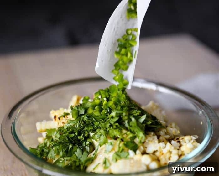Adding diced jalapeno to the corn salad mixture