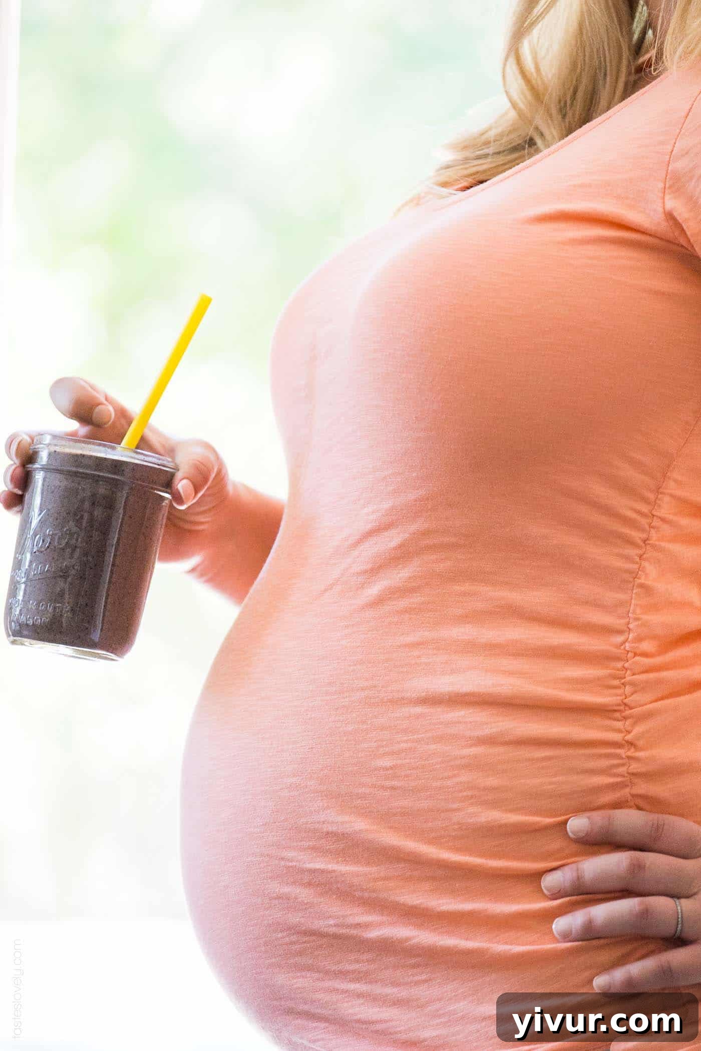 Pregnant woman enjoying a vibrant superfoods smoothie, signifying healthy prenatal nutrition.