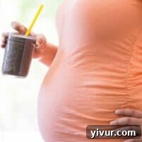 Pregnant woman holding a homemade healthy superfood smoothie.
