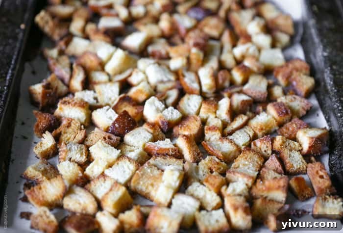 Crispy Garlic Parmesan Croutons 14 After baking: Crispy, golden brown garlic parmesan croutons piled on a baking sheet, glistening with oil and cheese.