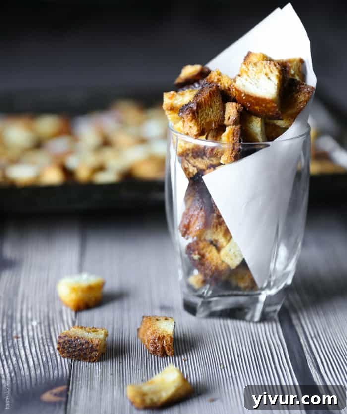 Crispy Garlic Parmesan Croutons 15 A close-up shot of a bowl filled with an abundance of perfectly golden, crispy garlic parmesan homemade croutons.