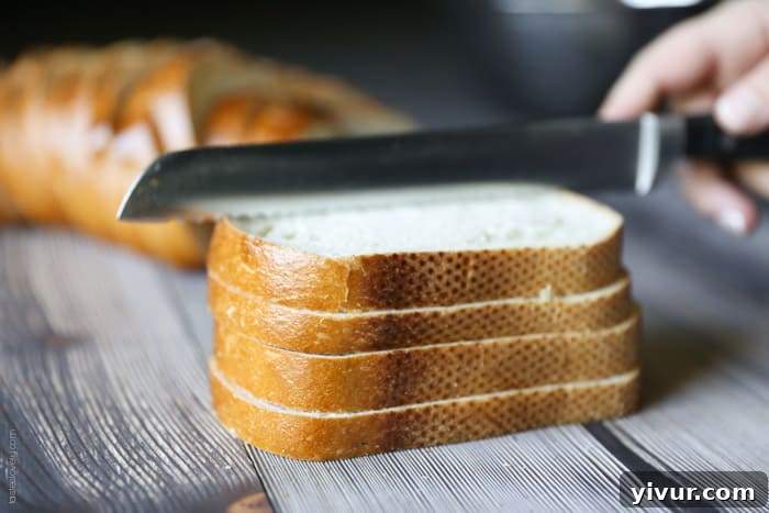 Crispy Garlic Parmesan Croutons 4 Several slices of sourdough bread neatly stacked on a cutting board, ready for slicing into croutons.