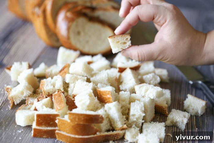 Crispy Garlic Parmesan Croutons 8 A pile of perfectly cubed sourdough bread pieces on a cutting board, ready for seasoning.