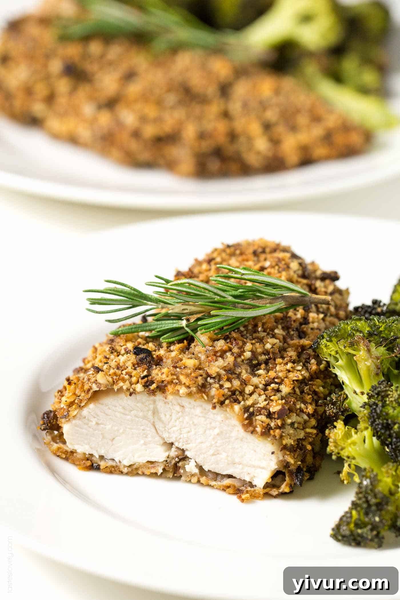 a piece of Almond Crusted Chicken on a plate next to roasted broccoli