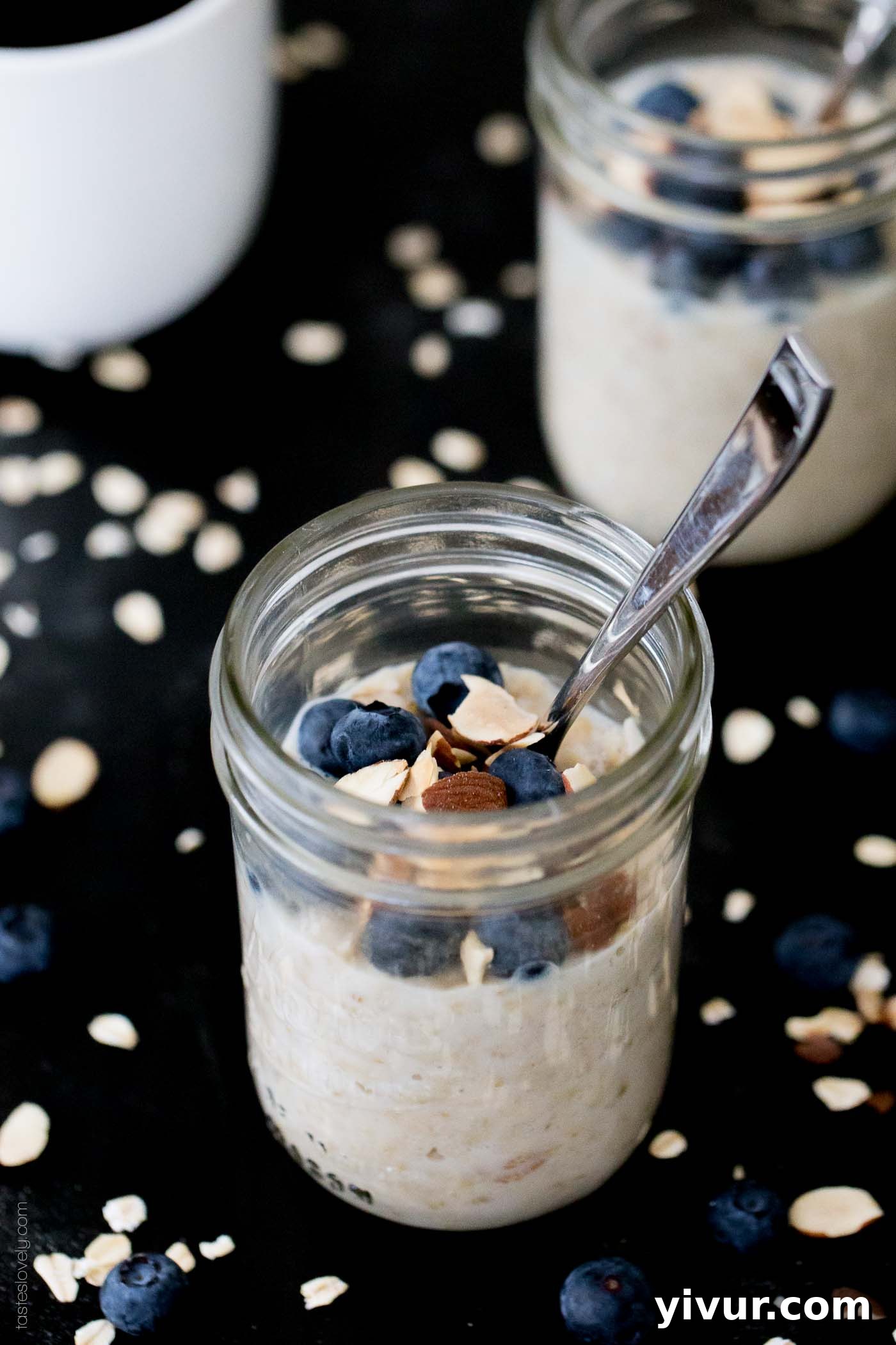 A jar of blueberry overnight oats in a glass mason jar with a silver spoon, ready to be enjoyed.