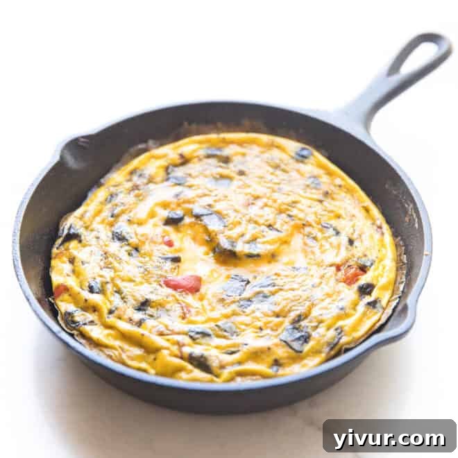 A delicious frittata in a rustic cast iron skillet against a clean white background.