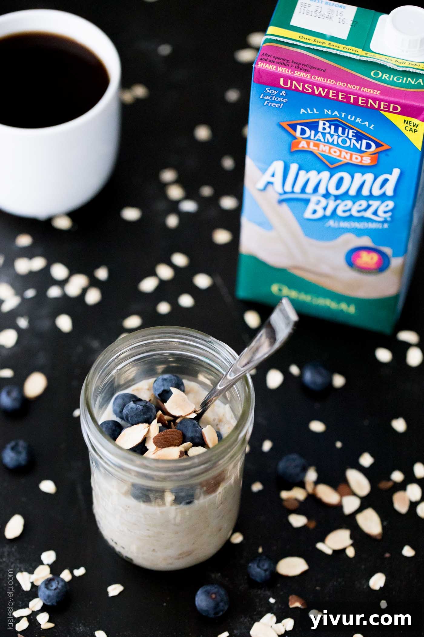 Oatmeal in a glass mason jar next to a container of unsweetened almond milk and a cup of coffee, illustrating the key ingredients.
