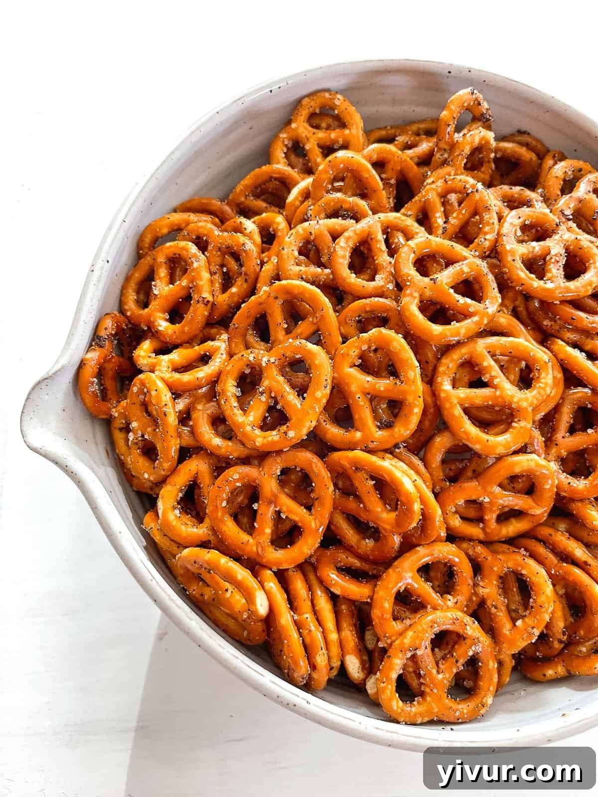 Effortless Fiery Pretzel Crunch 2 A white bowl filled with spicy seasoned pretzels, ready to be enjoyed.