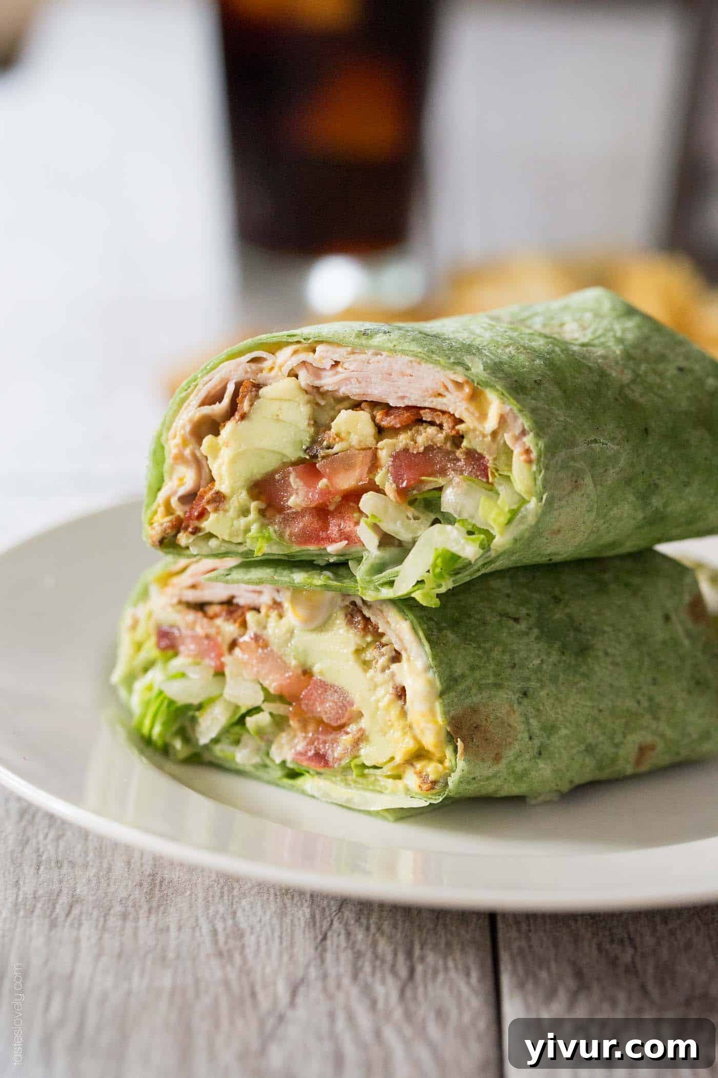 turkey, bacon, avocado, and tomato wrapped in a spinach tortilla and stacked on top of another wrap