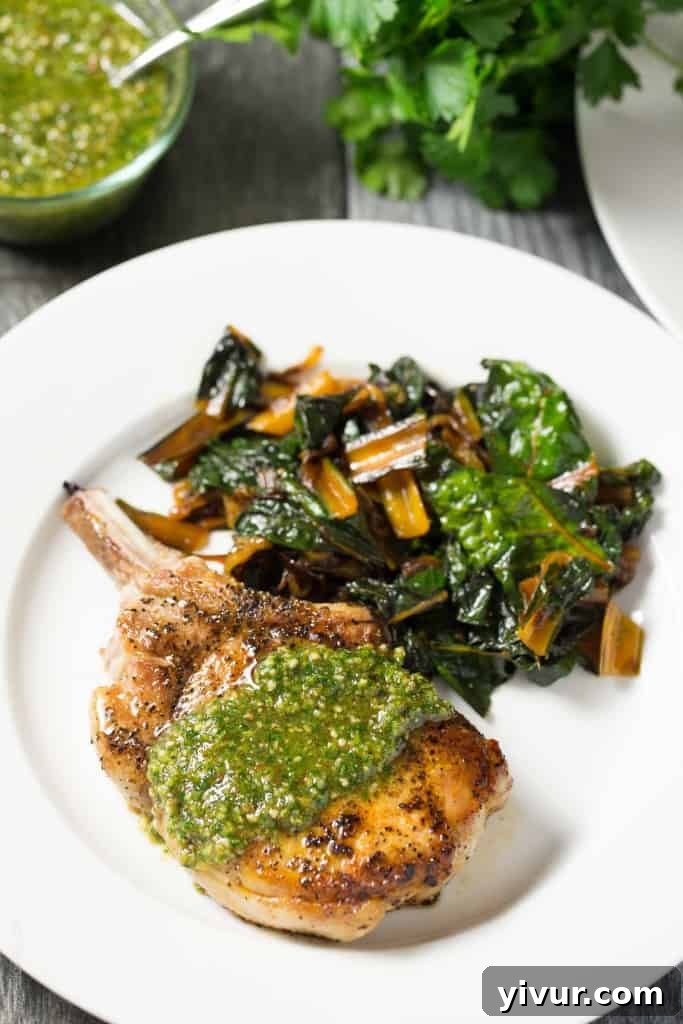 Sun-Kissed Pork Chops with Zesty Orange Parsley: Whole30 and Keto Perfect 3 A plate of two perfectly cooked bone-in pork chops, generously topped with bright orange parsley sauce, ready to serve.