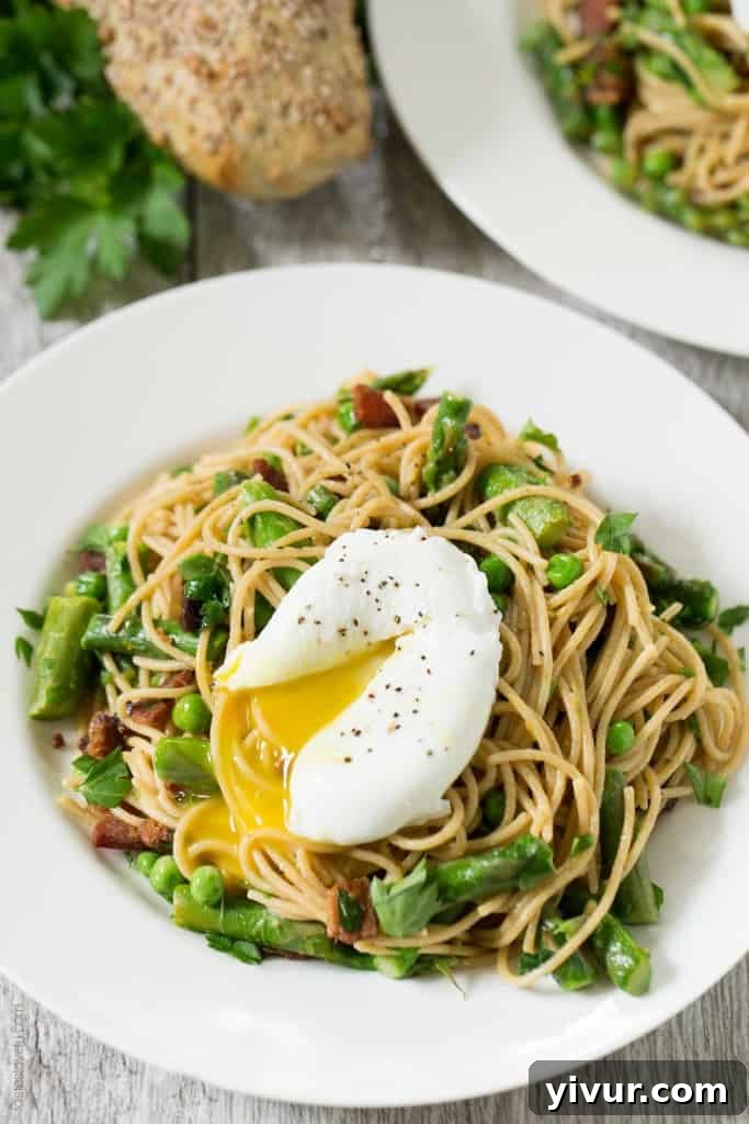 Close-up of Spring Pasta with Bacon and Poached Egg, highlighting the creamy yolk and fresh green ingredients.
