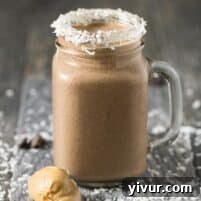 Peanut Butter Cocoa Coconut Smoothie in a glass, with fresh ingredients in the background