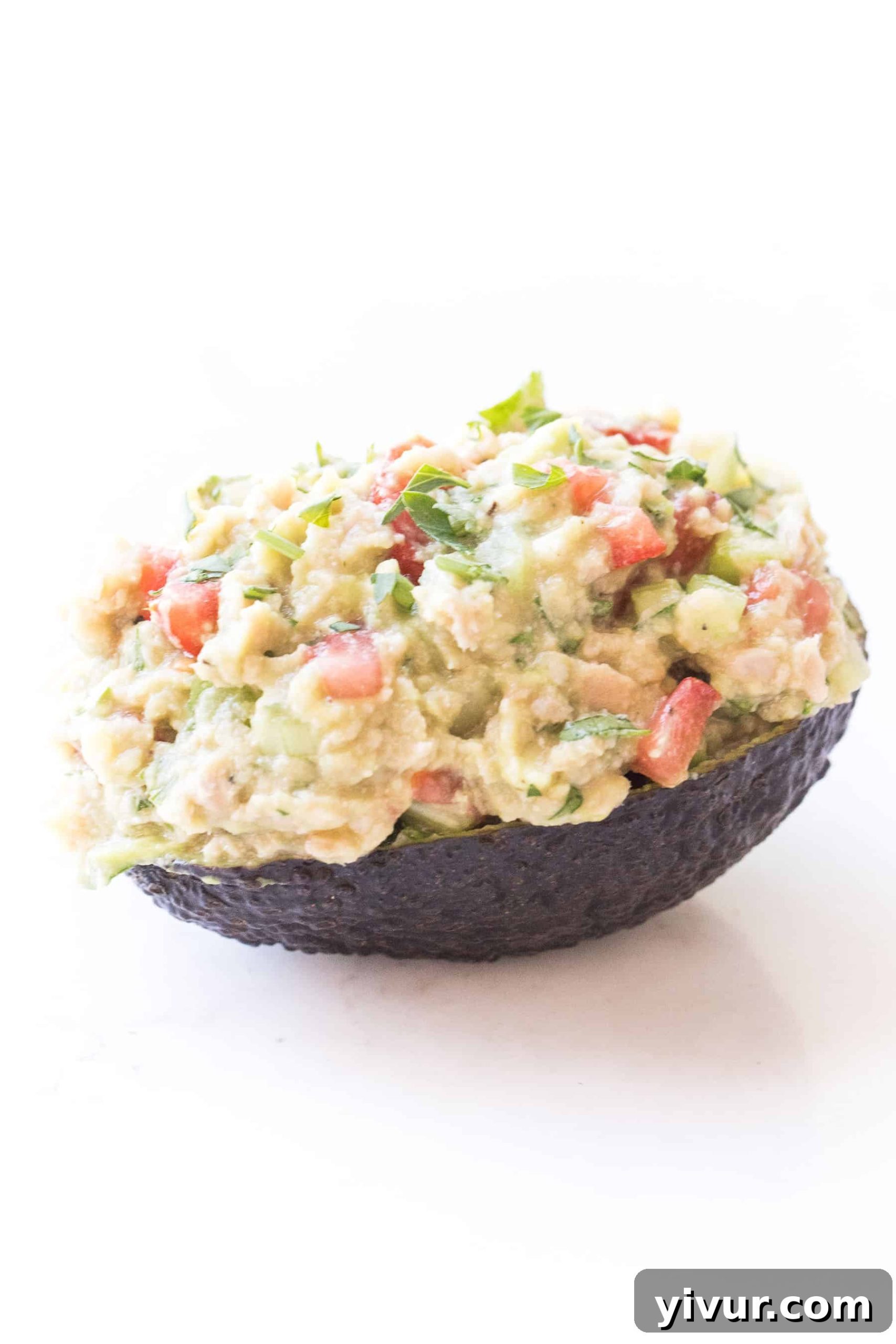 Freshly prepared avocado tuna salad in an avocado boat, presented on a clean white background