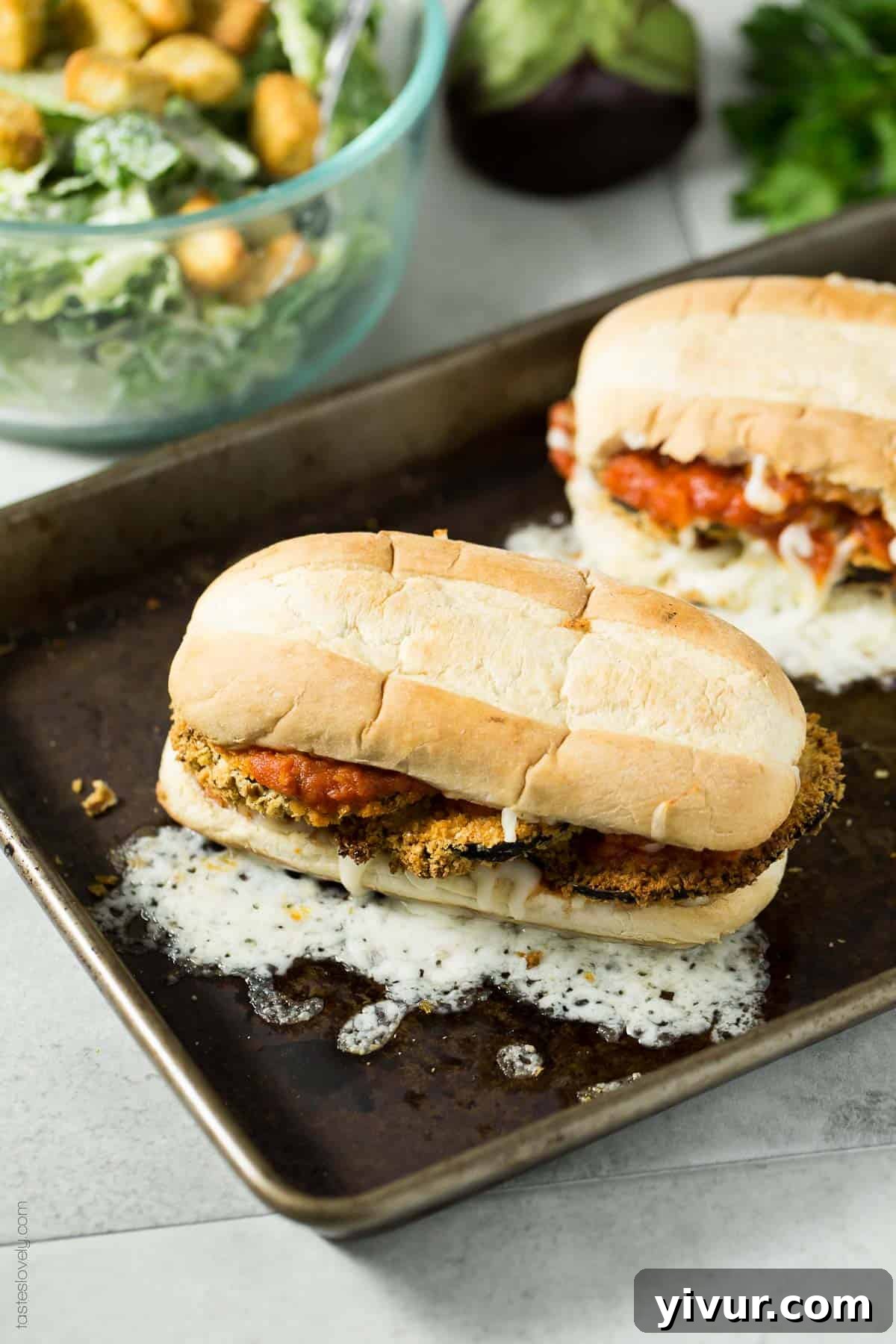 Close-up of a vegan crunchy baked eggplant sandwich melt being assembled on a toasted roll.