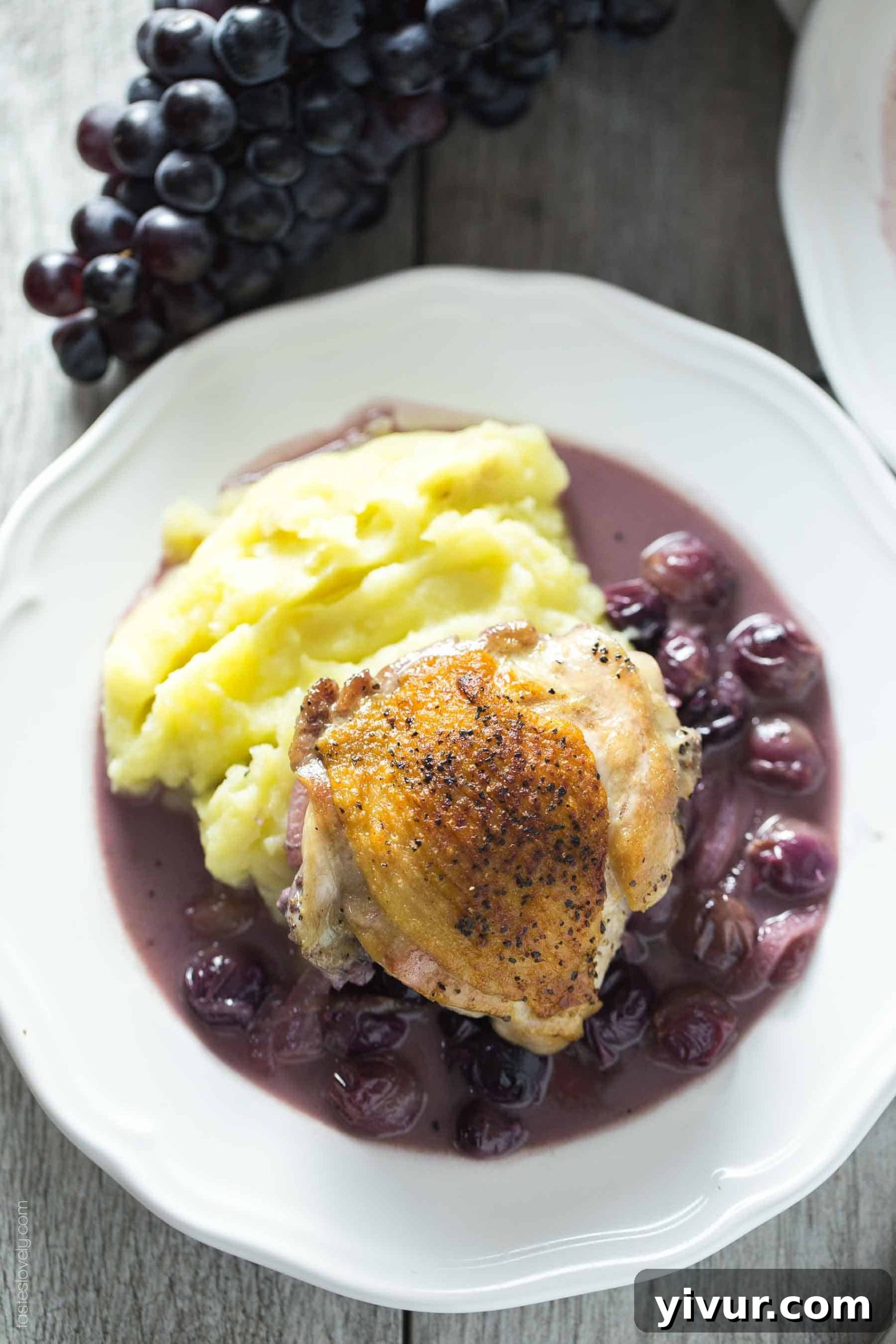 A close-up view of the braised chicken thighs and vibrant purple grapes simmering in the rich, aromatic sauce