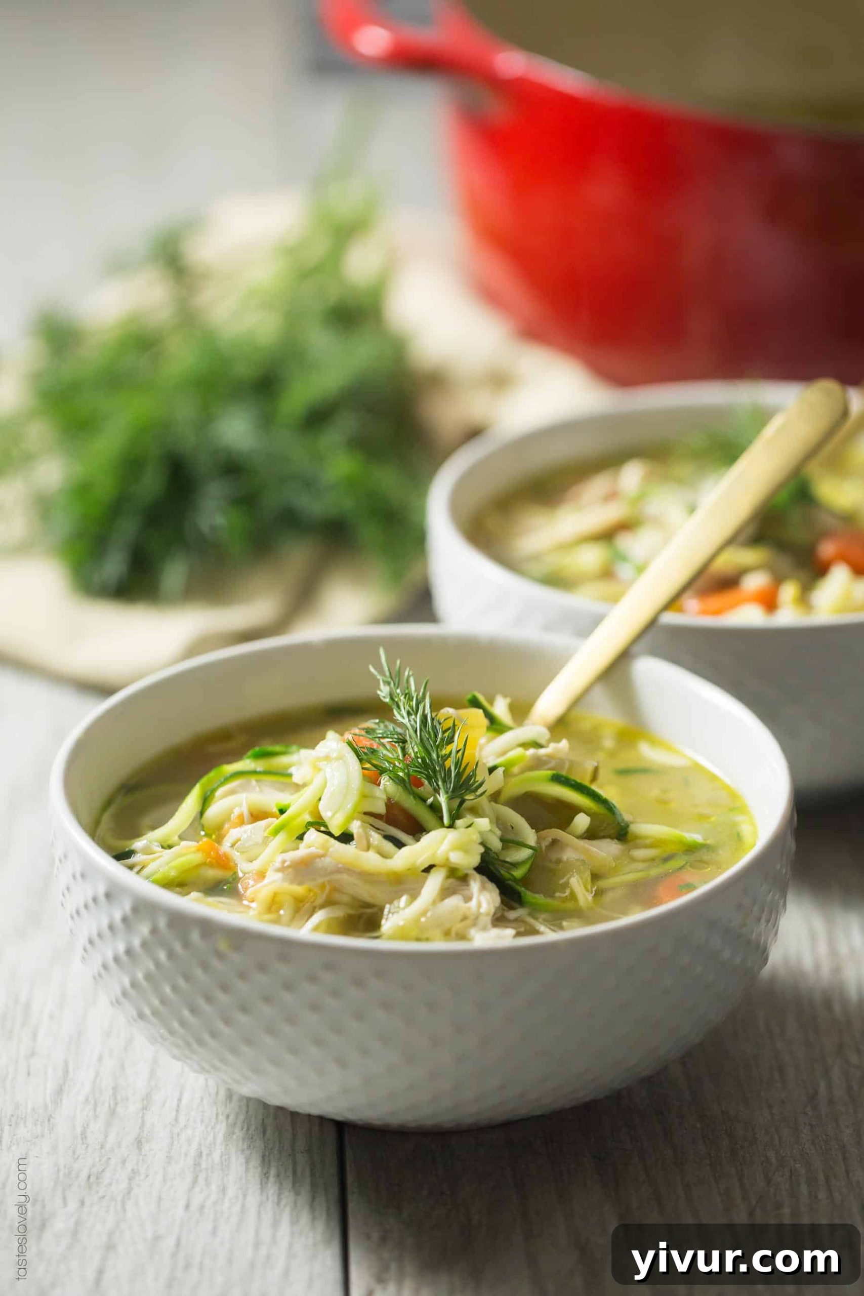 Bowl of healthy Whole30 Keto Chicken Zoodle Soup with shredded chicken and fresh herbs