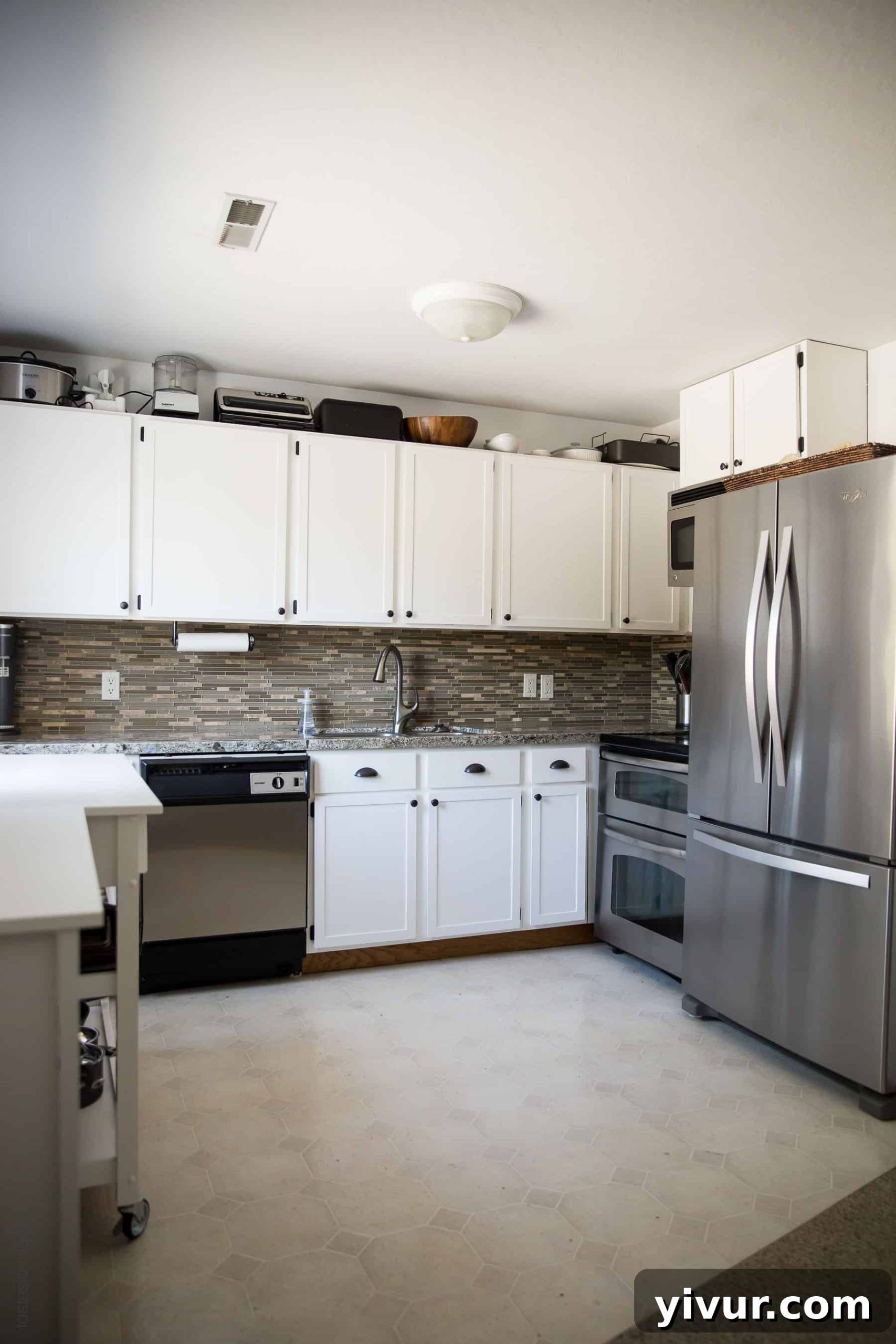 Close-up of transformed kitchen showing white cabinets and integrated stainless steel dishwasher