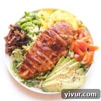 bbq chicken salad with avocado, bacon, bell pepper, tomatoes and green onions on a white plate and background