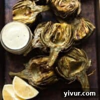 Paleo & Whole30 Grilled Artichokes with a lemon garlic basting oil and a lemon garlic aioli dipping sauce.