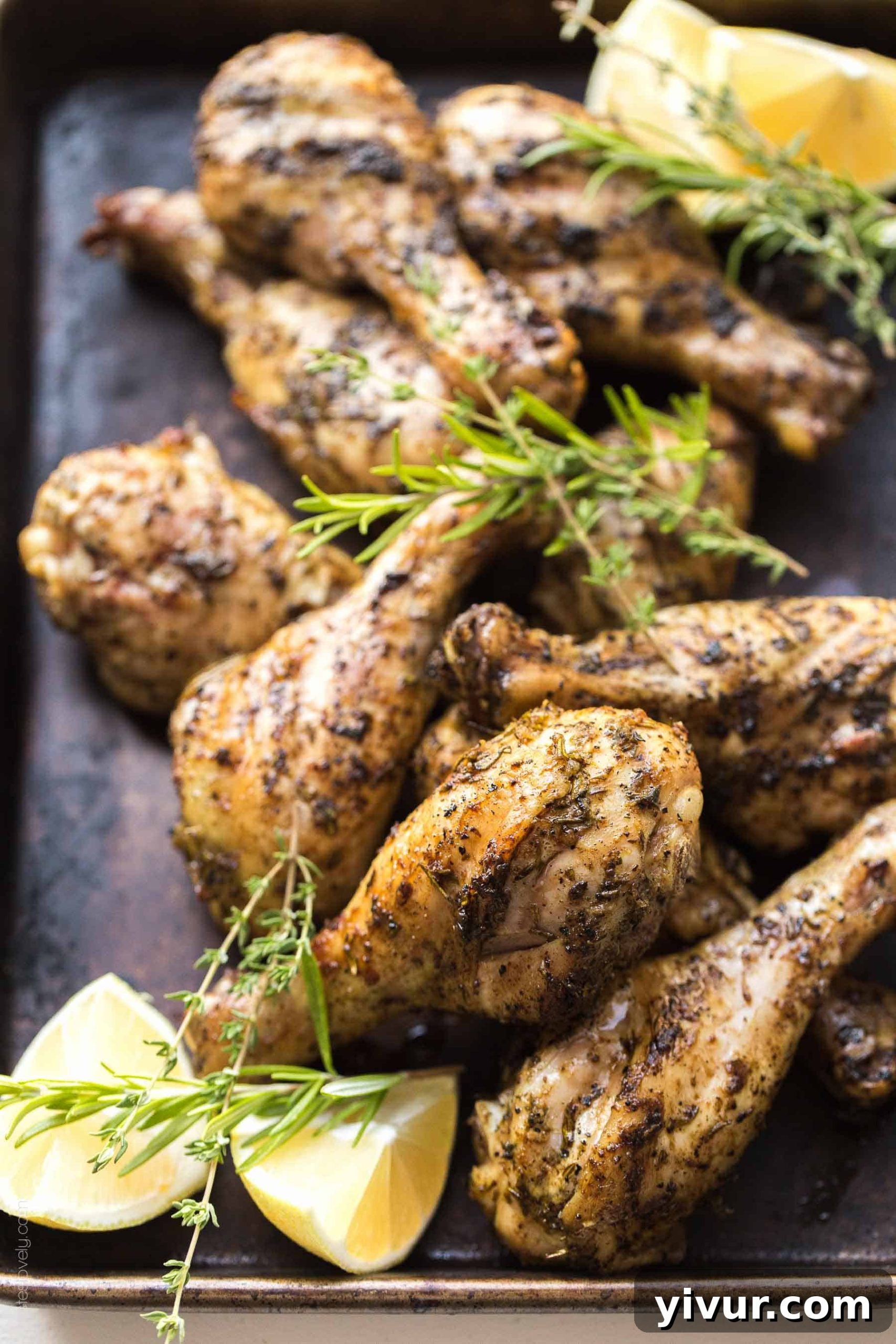 A plate of freshly grilled Lemon Herb Chicken Drumsticks, glistening and golden-brown, served with fresh lemon wedges and a sprig of rosemary.