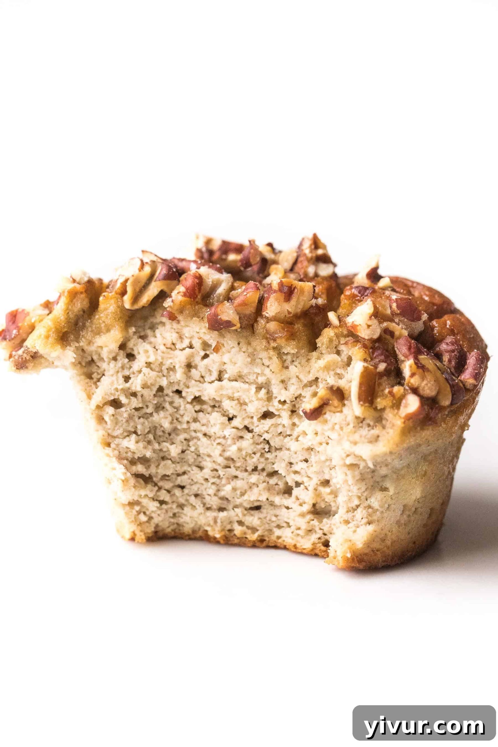 A paleo banana muffin with a bite taken out, revealing its moist interior and light texture.