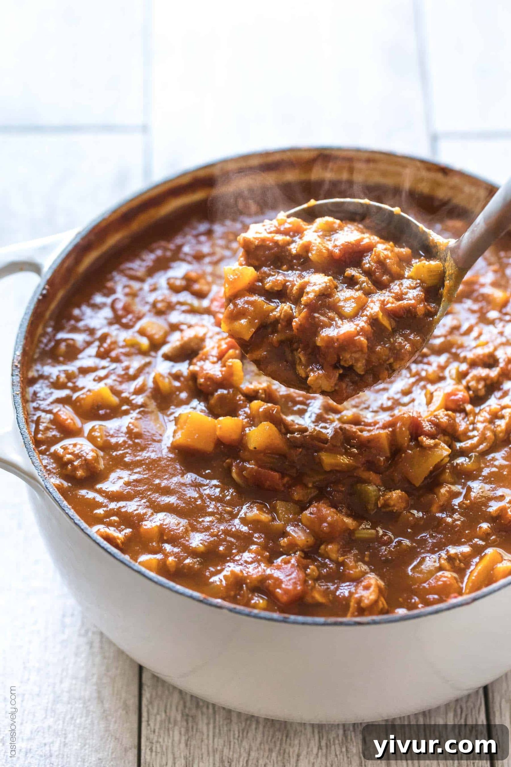 A large pot of Paleo & Whole30 Pumpkin Turkey Chili simmering on the stove, showcasing its rich, thick consistency and readiness for serving.