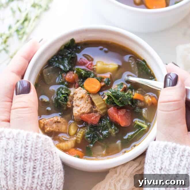 Wholesome Chicken and Kale Potato and Leek Soup 7 Hearty Italian Sausage & Vegetable Soup served in a white bowl.