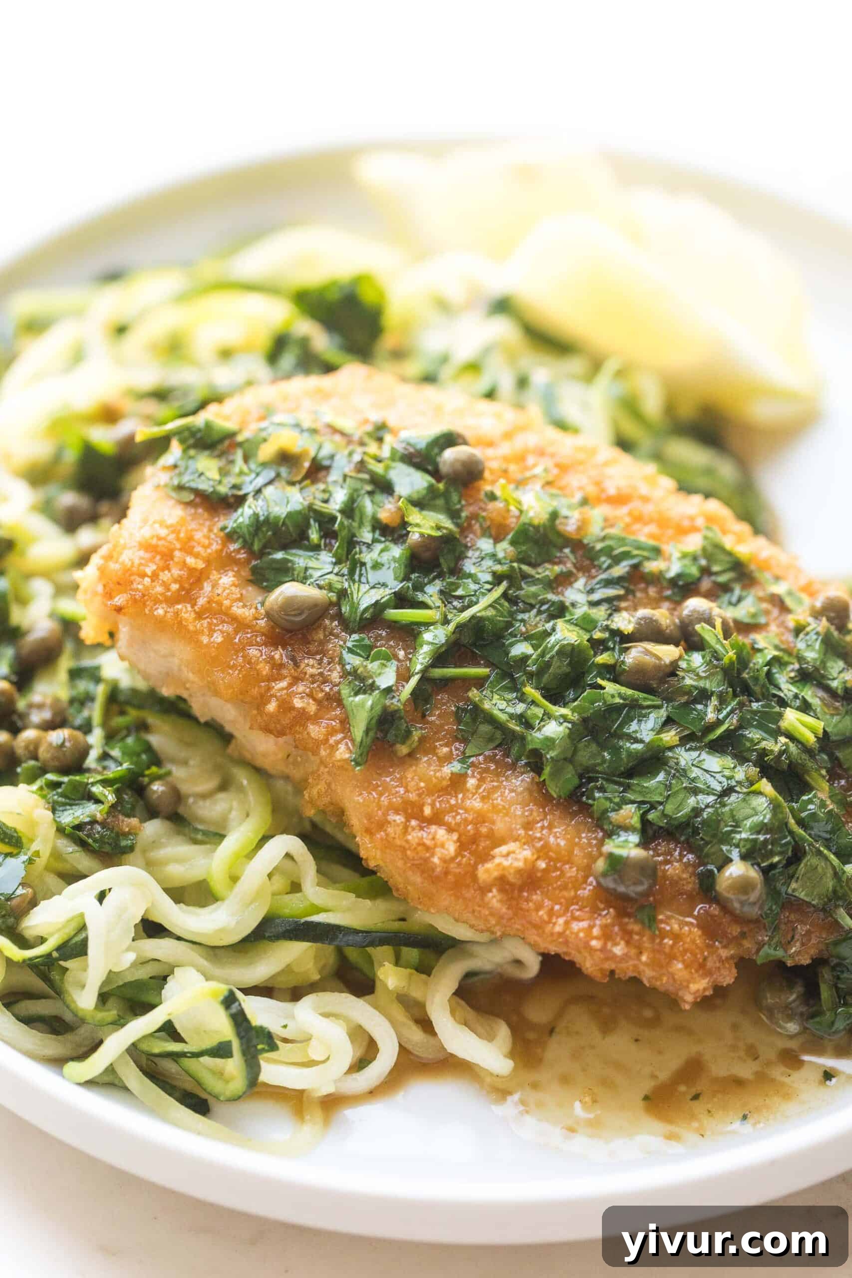 Close-up of crispy breaded lemon keto chicken piccata over zucchini noodles