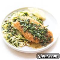 breaded lemon keto chicken piccata over zucchini noodles on a white plate and background
