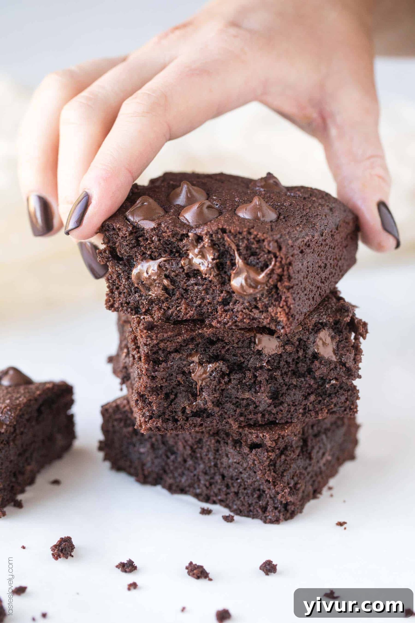 Decadent Dairy Free Keto Brownies Almond Flour 5 A close-up of three stacked keto brownies, showcasing their rich chocolatey texture, gooey centers, and scattered chocolate chips.