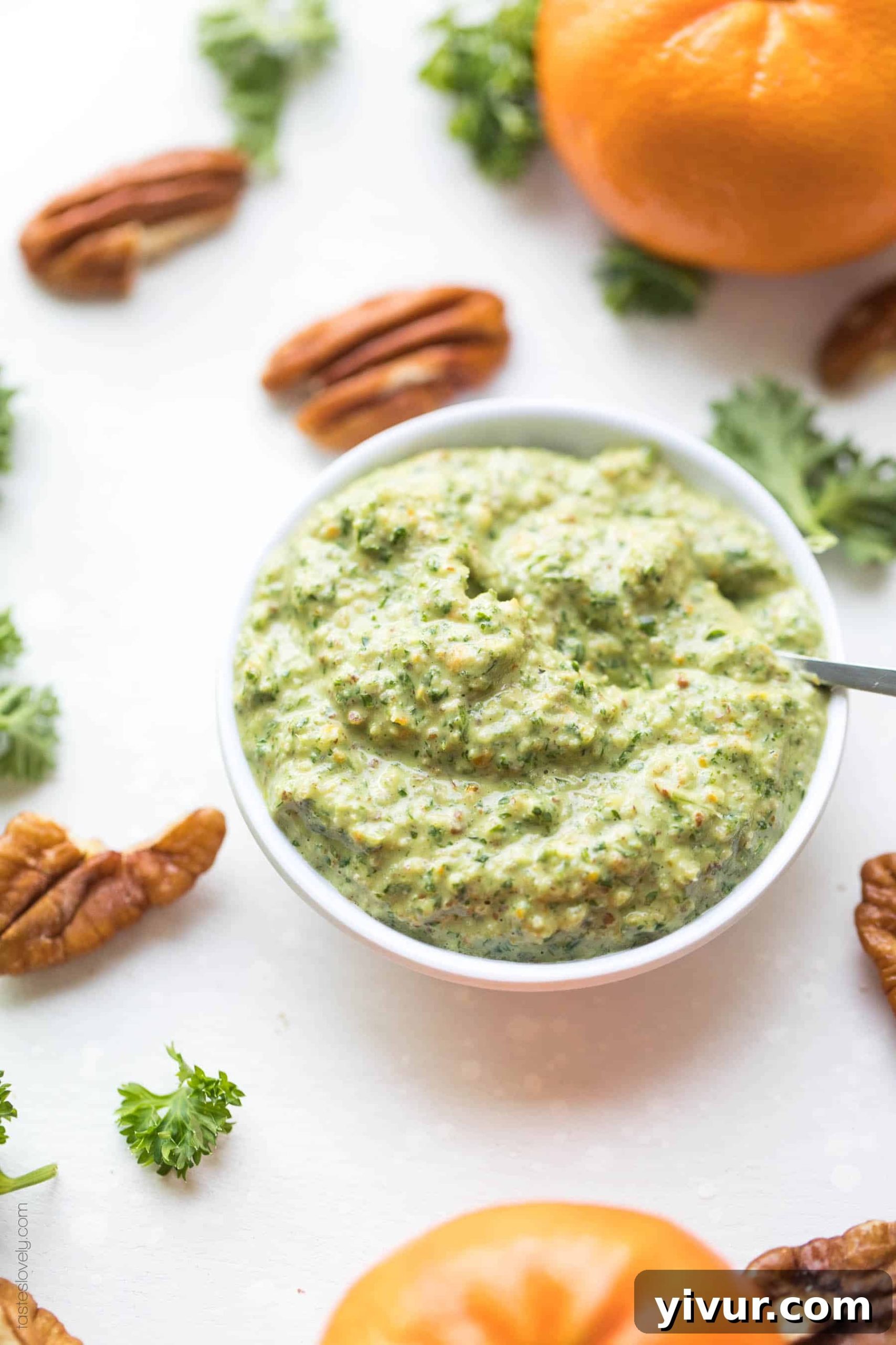 Freshly blended Whole30 and Keto Orange Parsley Sauce in a small white bowl, garnished with a sprig of parsley and an orange slice, ready to serve.
