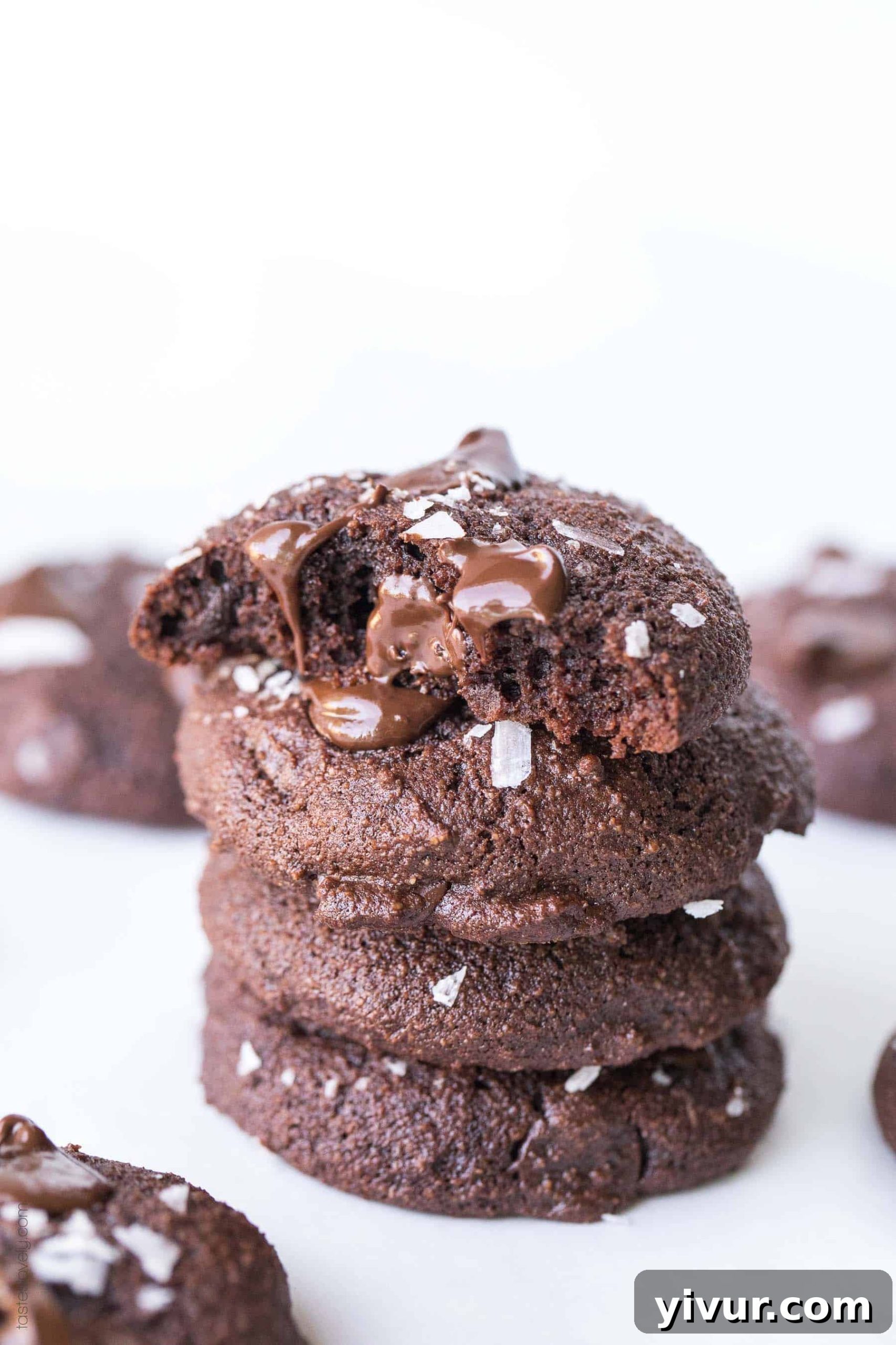 Keto Fudgy Sea Salt Chocolate Cookies 6 An overhead shot of two Keto Salted Chocolate Brownie Cookies on a dark surface, emphasizing the flaky sea salt sprinkled on top.