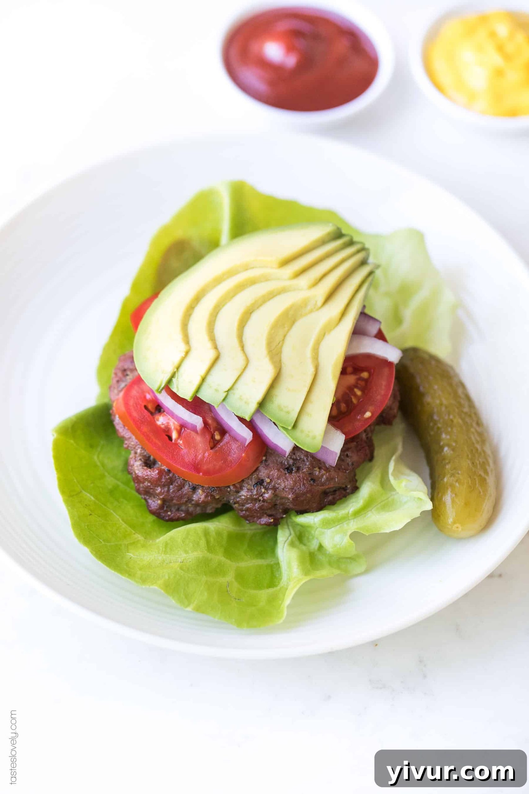 A cooked keto burger patty resting on a cutting board, ready to be served on a lettuce bun with fresh toppings.