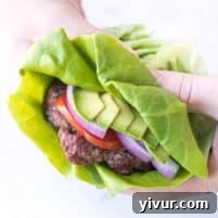 a hand holding a burger that has a lettuce wrap