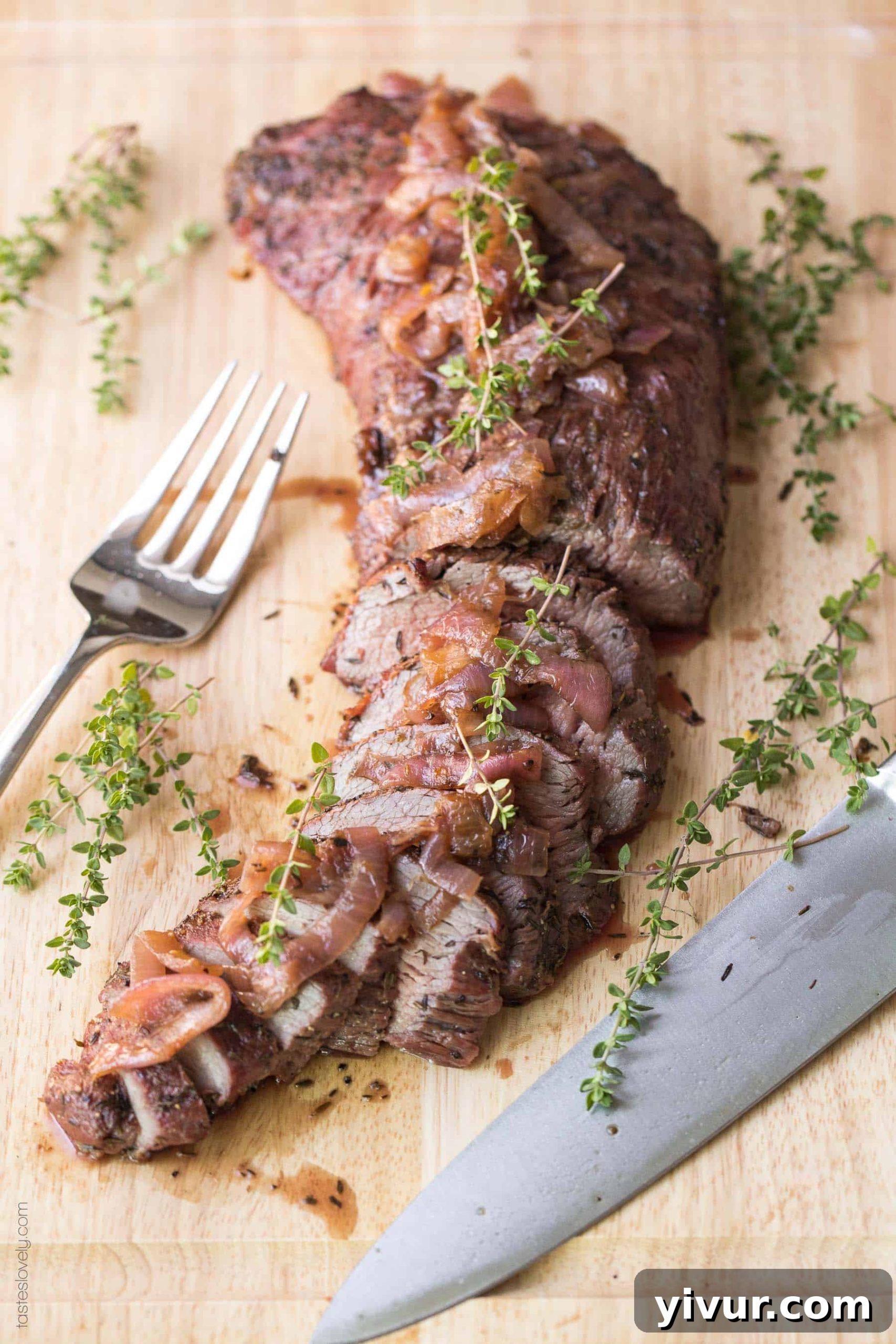 A perfectly cooked cut of tri tip resting on a wooden cutting board, garnished with fresh herbs, ready to be sliced.
