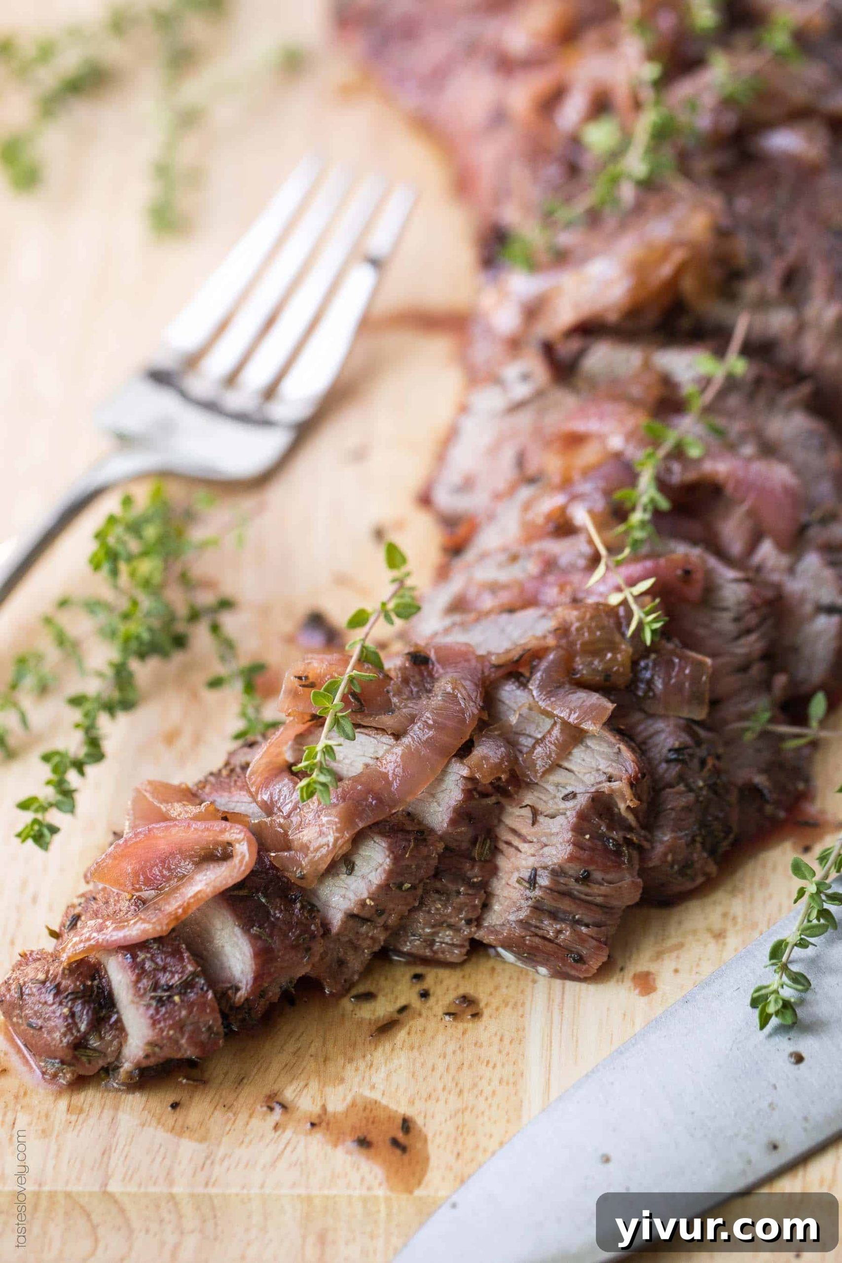 An close-up shot of grilled tri tip steak adorned with a generous topping of caramelized red wine vinegar sautéed red onions.