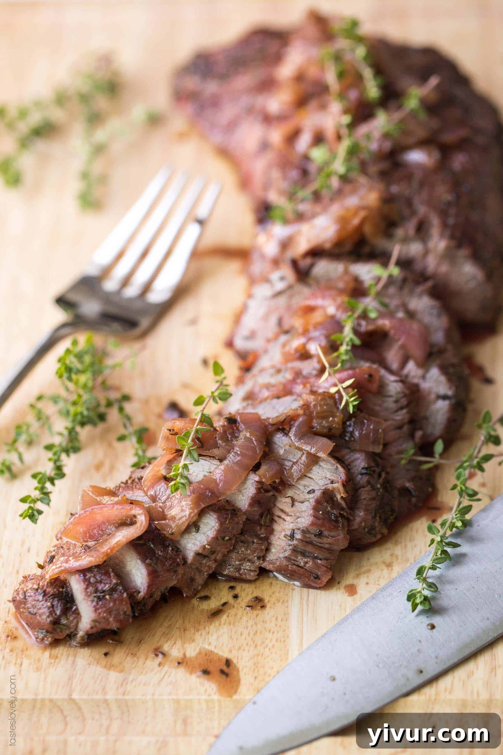 A stunning final presentation of a sliced tri-tip steak, generously topped with red wine vinegar sautéed red onions, resting on a serving platter.