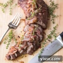 A delicious tri tip marinated, then cooked, sliced, and topped with grilled onions, showcased on a plate.