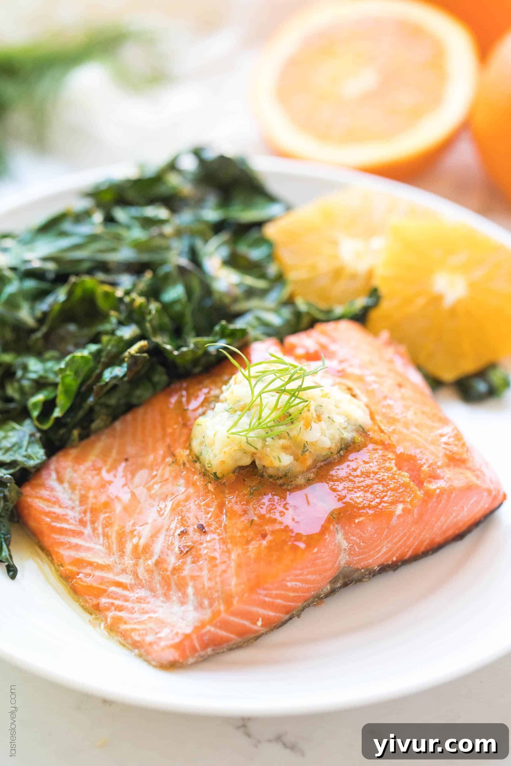 Vibrant Orange Dill Butter Salmon Whole30 Paleo Keto Friendly 2 Pan-seared salmon filet with a dollop of orange dill butter, garnished with fresh dill and orange slices on a white plate.