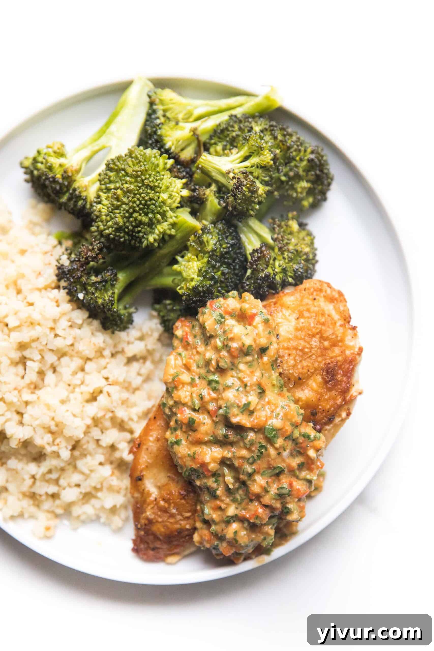 chicken topped with mediterranean salsa on a white plate with broccoli and cauliflower rice