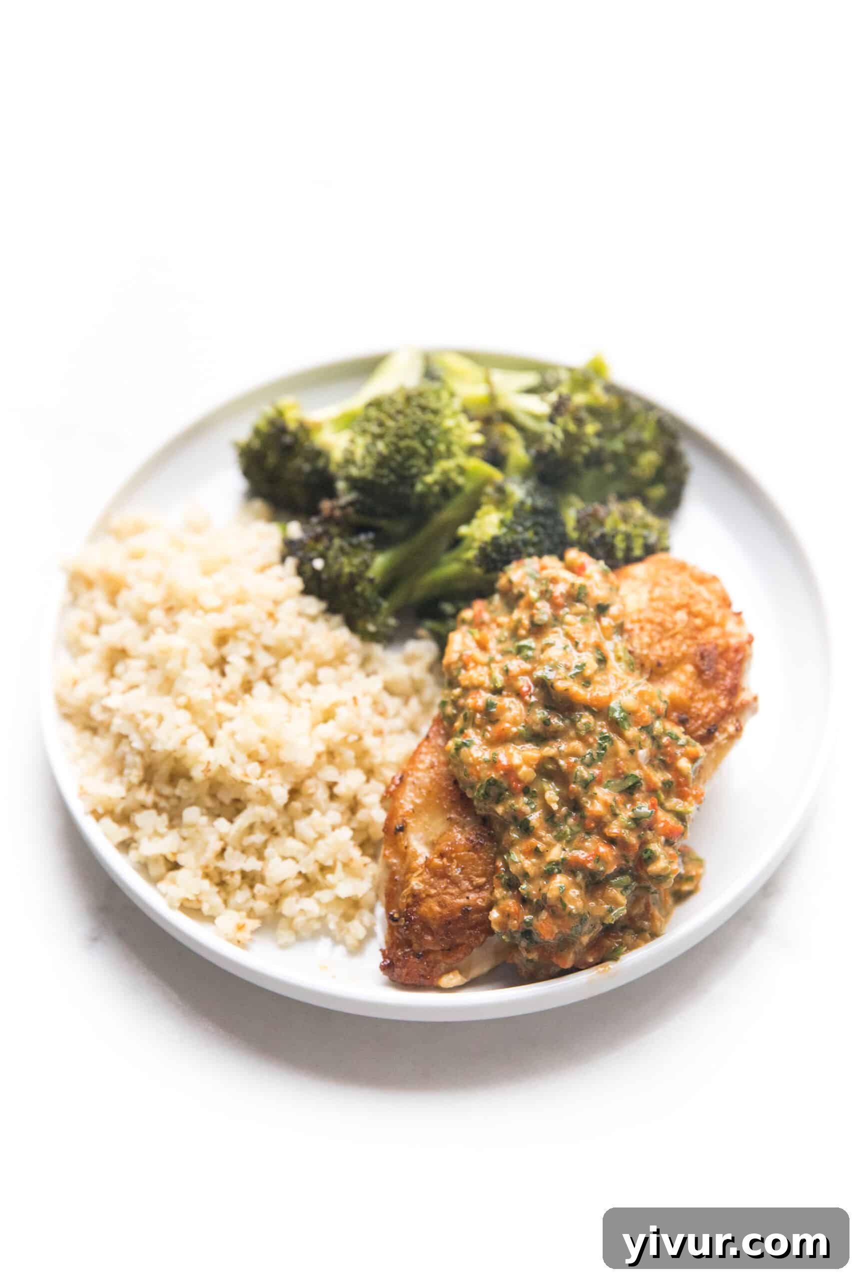 chicken topped with mediterranean salsa on a white plate with broccoli and cauliflower rice
