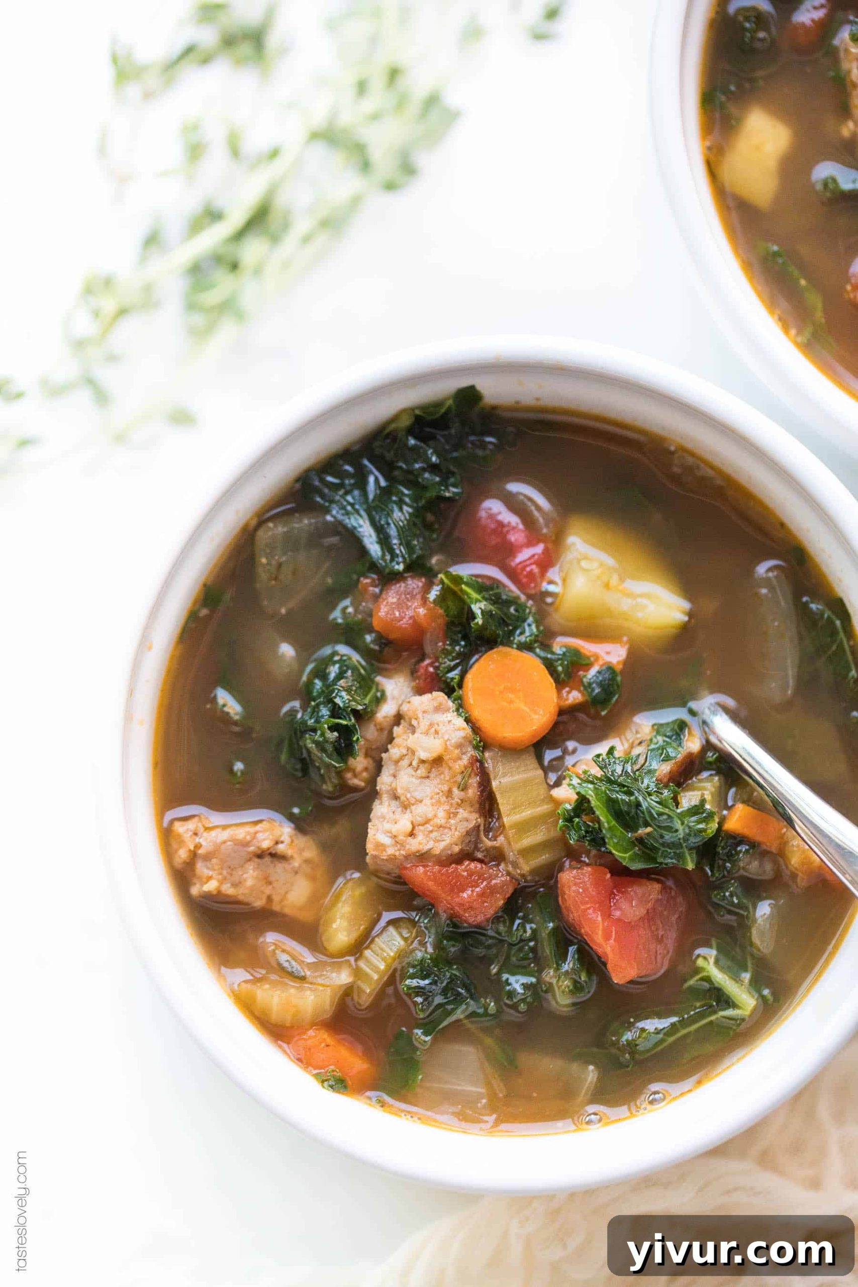 A steaming bowl of Whole30 Keto Italian Sausage and Kale Vegetable Soup garnished with fresh herbs, ready to be enjoyed.