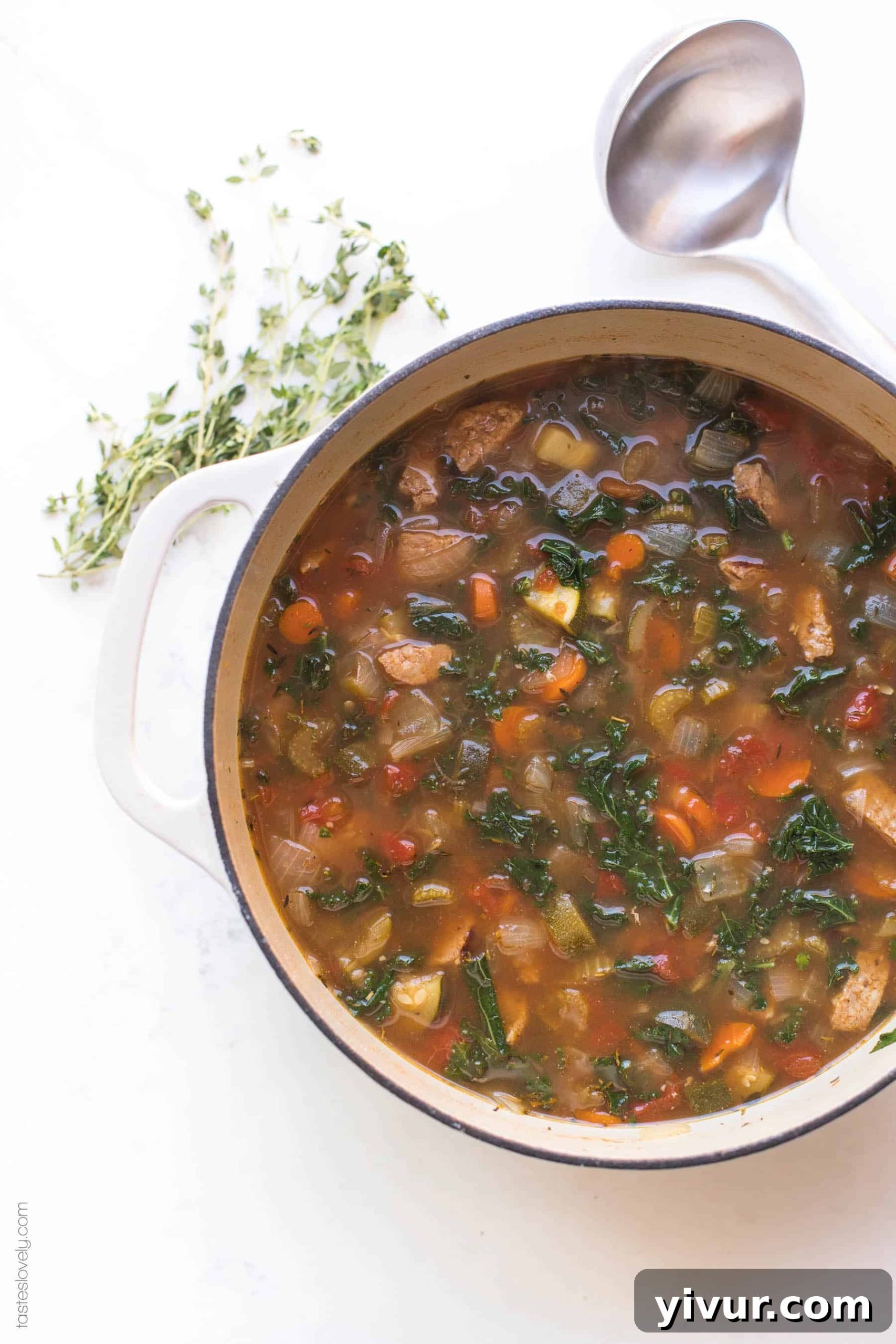 A large dutch oven filled with the simmering Whole30 Keto Italian Sausage and Kale Vegetable Soup, ready to be served.