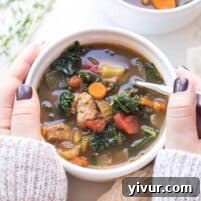 A close-up shot of a bowl of Italian Sausage and Kale Vegetable Soup, highlighting the rich broth and hearty ingredients.